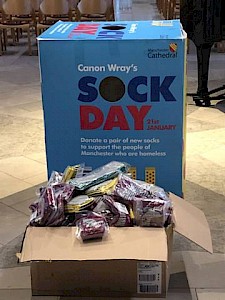 A blue sock collection box in front of a stained glass window